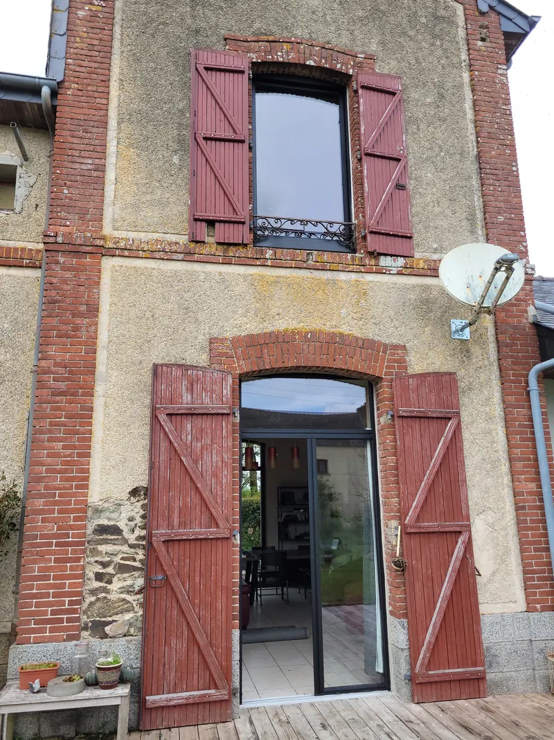 Porte et fenêtres aluminium posées sur une façade en pierre et brique